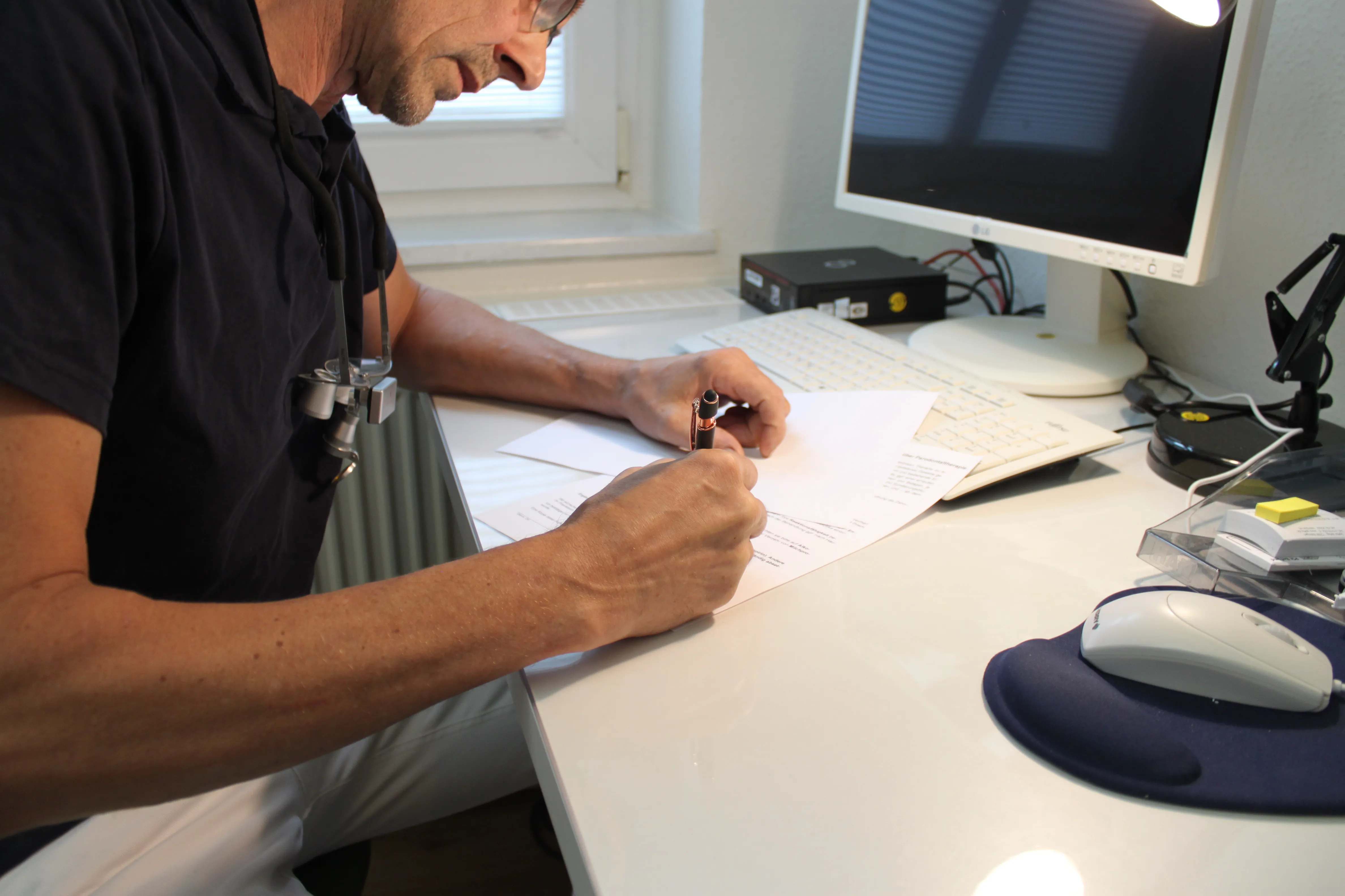 Dr. Roman Kubetschek schreibt mit einem Stift auf einem Dokument am Schreibtisch