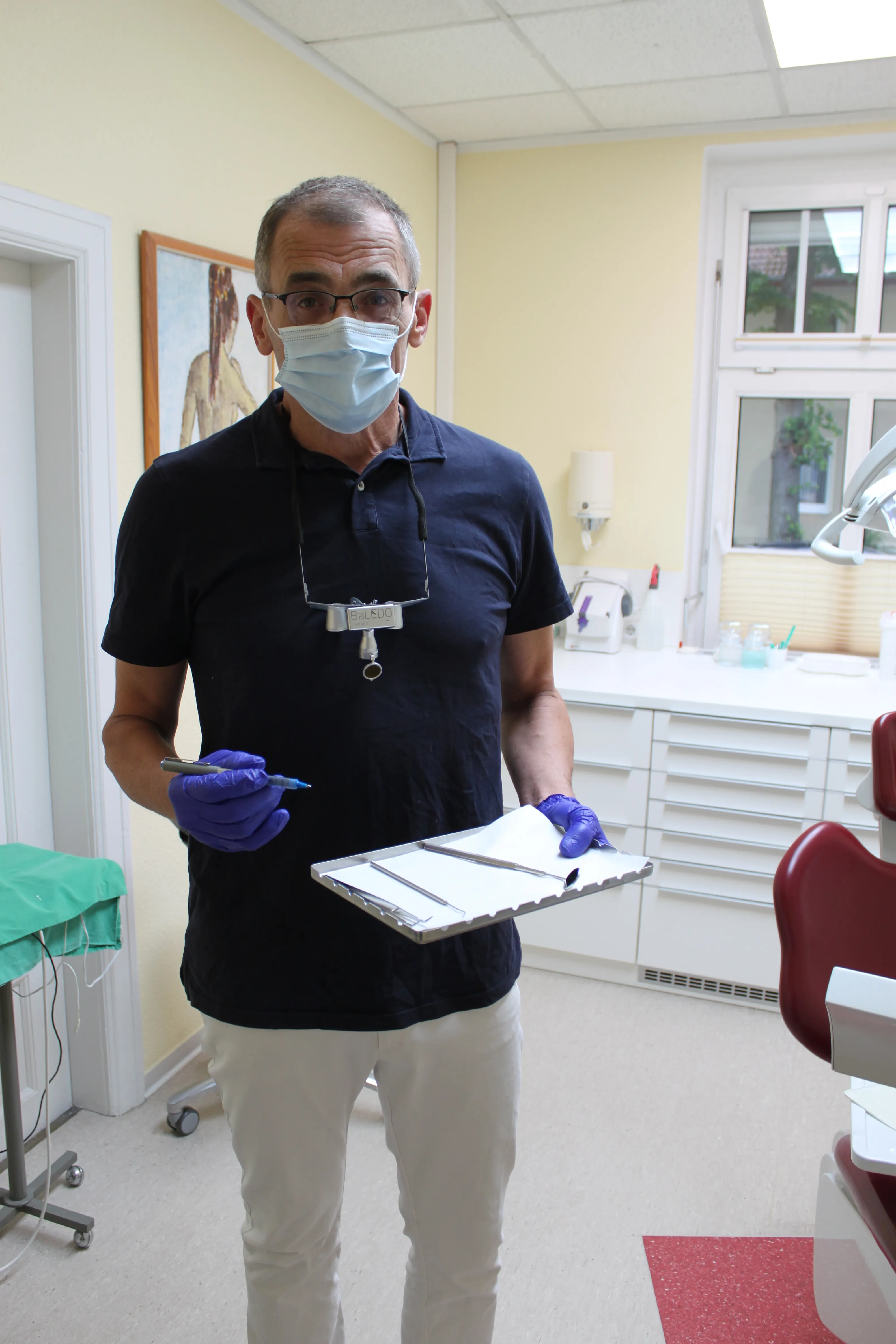 Dr. Roman Kubetschek mit Mundschutz und Instrument bei der Arbeit